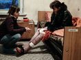 Roza, left, an outreach worker with Club Svitanok, kneels in 2011 across from Katya, 37, who is HIV-positive and struggling with drug addiction, in a Donetsk hospital where she was being treated for pneumonia. Ukraine, 2011.